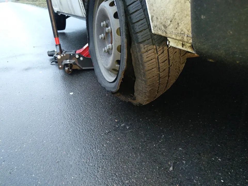 Beschädigter Reifen an einem aufgebockten Fahrzeug