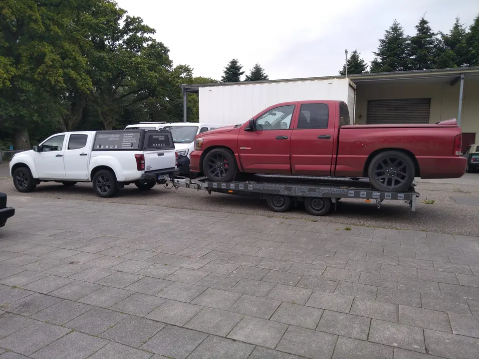 Mehrere Fahrzeuge auf und neben einem Transportanhänger