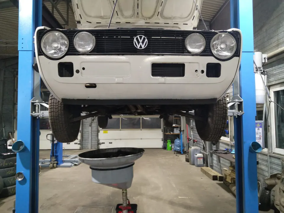 Klassischer weißer Pkw mit geöffneter Motorhaube auf der Hebebühne