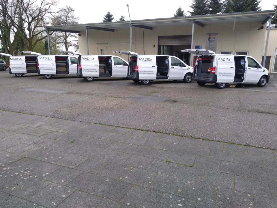 Reihe ausgestatteter Servicefahrzeuge vor dem Werkstattgebäude